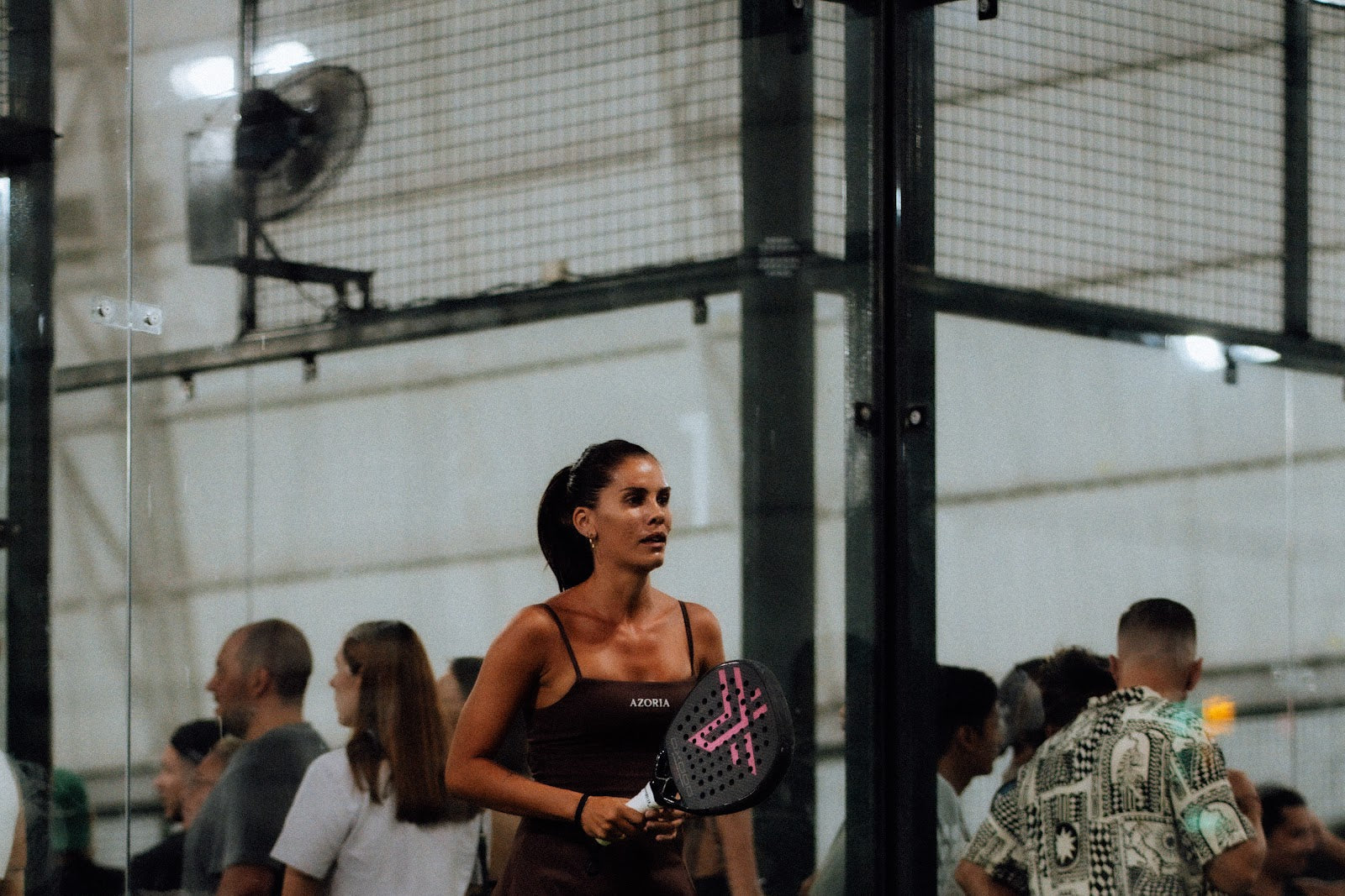 Padel player walking on court past a crowd at a Bali padel club in Uluwatu